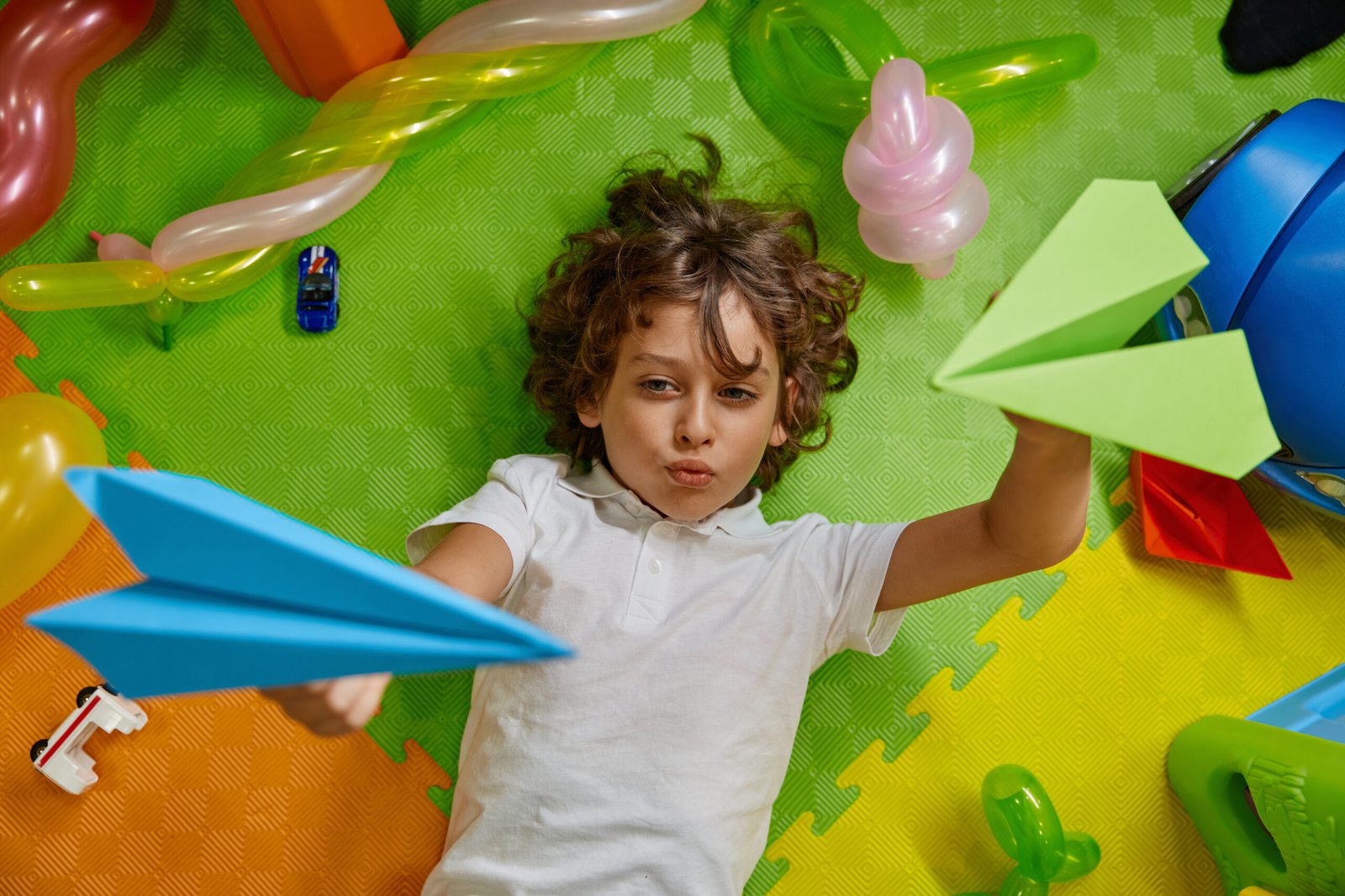 Little boy kid playing paper planes on floor of childcare center